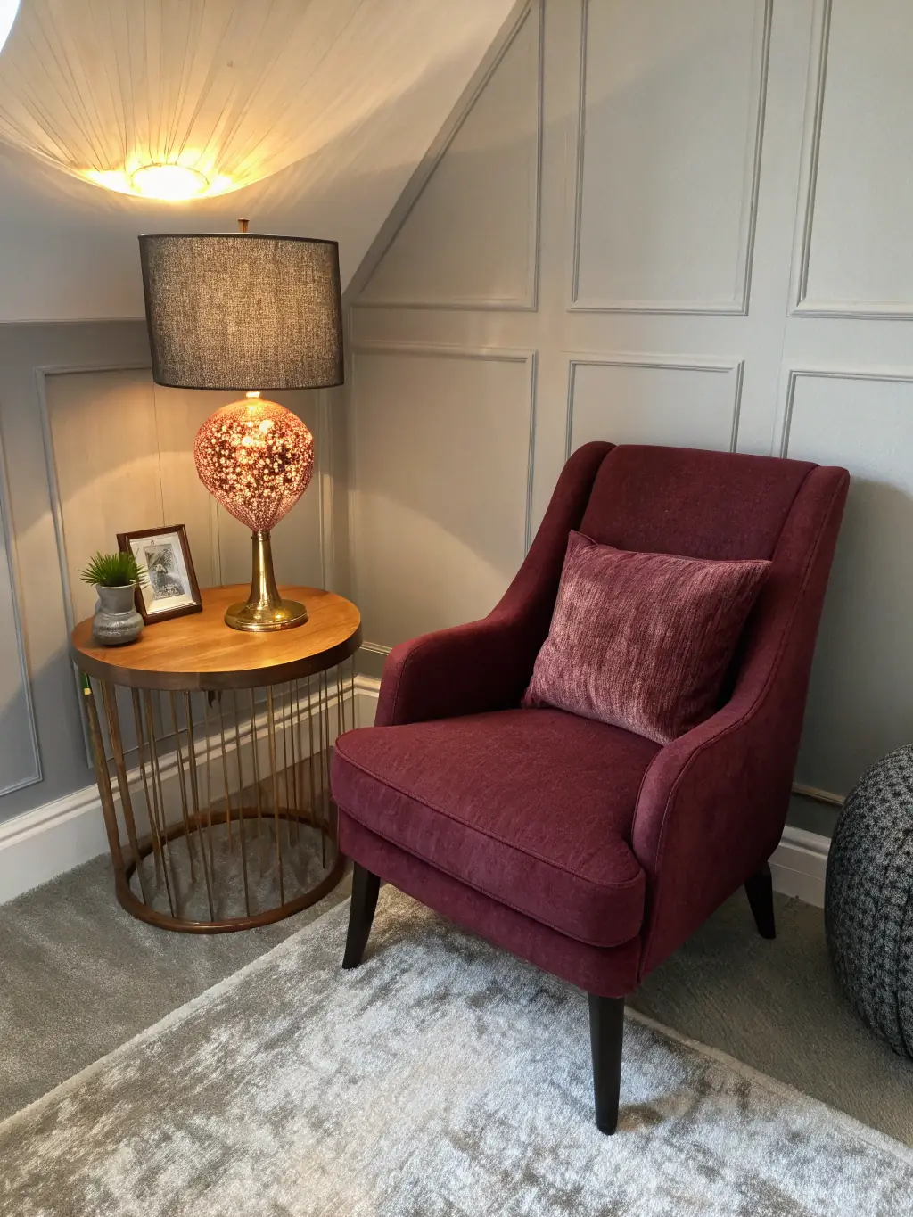 A plush, velvet armchair and a vintage floor lamp in the corner of a hotel room, creating a cozy reading nook with soft, warm lighting.